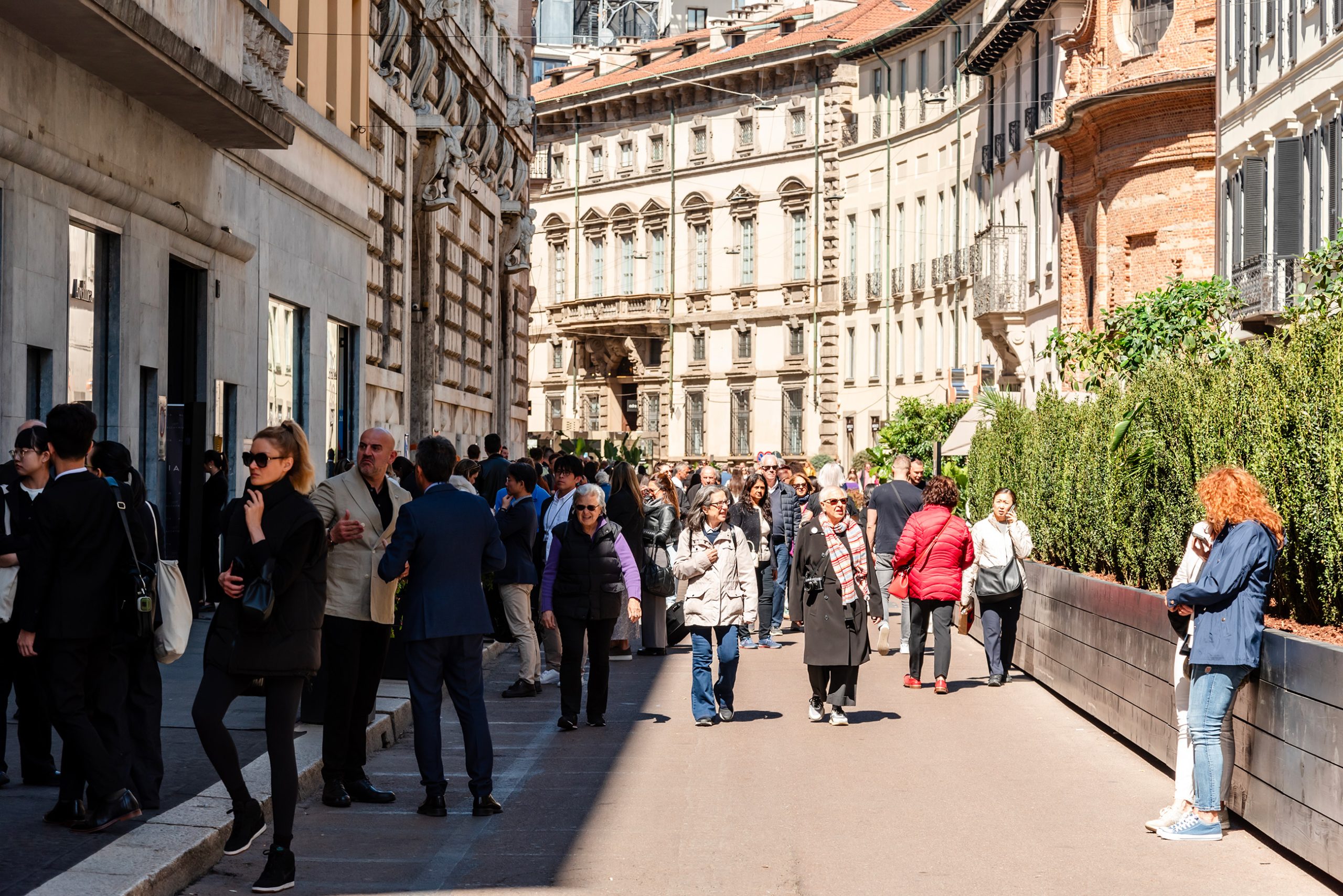 Via Durini, Milano: folla di persone passeggia tra le boutique di lusso. Architettura storica, negozi moda, turismo a Milano, shopping di alta moda, stile italiano, giornata soleggiata.